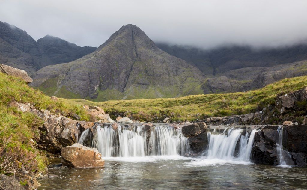 A rumbling waterfall with craggy dark mountain peaks in the background